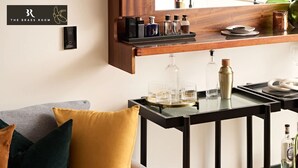 A modern living area with a sofa, a coffee table, and a small bar area with bottles and glasses. - The Brass Banana in Petersham (Sydney)