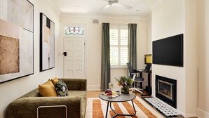 Un salon comprenant un canapé, une table basse, une cheminée, un téléviseur et une porte ornée d’un vitrail.