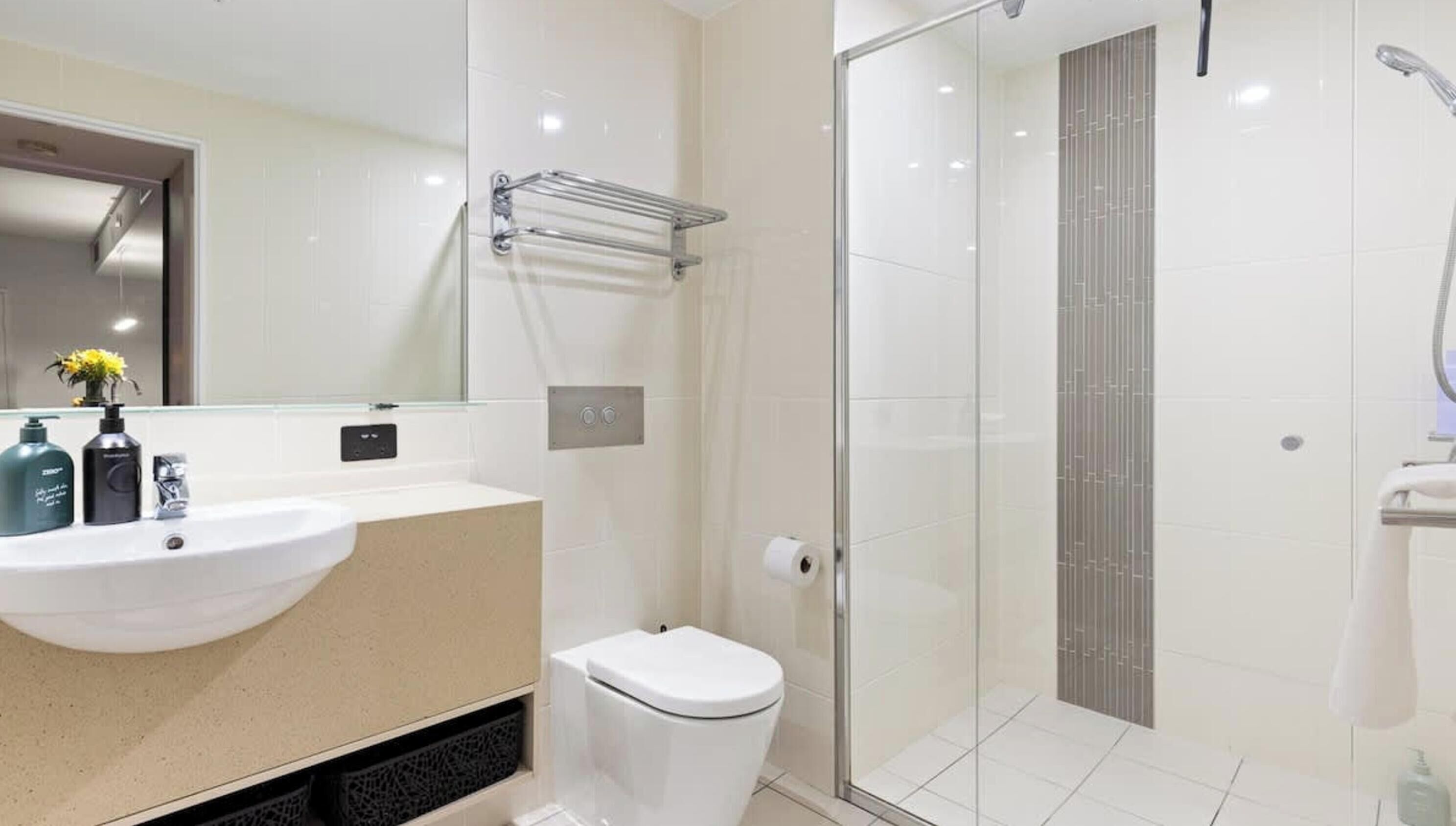 Un baño moderno con cabina de ducha de vidrio, un lavamanos blanco y un inodoro.