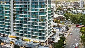 Ett hotell med flera våningar och en modern fasad av glas, beläget i ett stadsområde med en livlig gata och andra byggnader i bakgrunden.