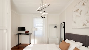 Camera d'albergo con un letto, una scrivania con un portatile, una televisione e un quadro appeso al muro.