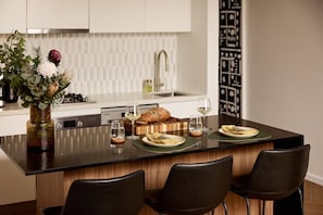 Una cocina moderna con una isla central, un comedor con sillas y un jarrón decorativo con flores.
