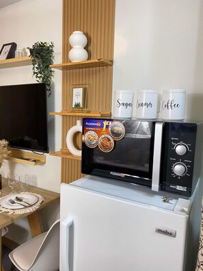 Une petite cuisine équipée d’un four à micro-ondes, d’une machine à café et d’un réfrigérateur.