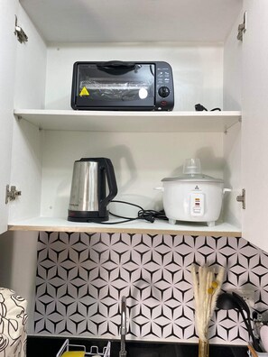 Una cocina con microondas, cafetera y olla de cocción lenta sobre estantes.