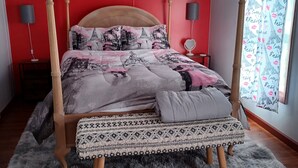 A four-poster bed with a patterned bedspread, a bench at the foot, and a wall tapestry of Parisian landmarks. - Romantic couples bed & breakfast in secluded Strykersville NY (STRYKERSVILLE)