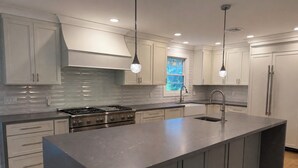 A modern kitchen with a large island, stainless steel appliances, and pendant lighting. - Fabulous 6-bedroom house with AC in charming Montclair Estate Section (Montclair)
