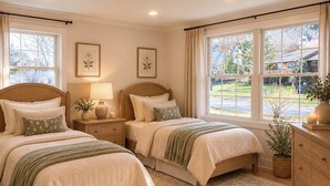 A bedroom with two beds, a nightstand, a dresser, and a large window with a view of the outside. - Fabulous 6-bedroom house with AC in charming Montclair Estate Section (Montclair)