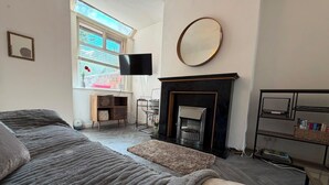 A modern living room with a fireplace, a flat-screen TV, and a large mirror. - Park4Free - Etihad & Co-op Live near- Nifty Find (Manchester)