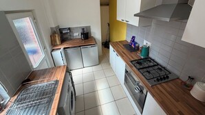 A compact kitchen with a washing machine, a gas stove, and a small countertop area. - Park4Free - Etihad & Co-op Live near- Nifty Find (Manchester)