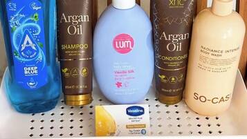 Uno scaffale con diversi prodotti per la cura dei capelli, tra cui shampoo e balsamo.