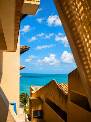 A view through a building's window overlooking a clear blue sky and turquoise sea.