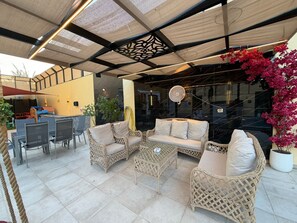 Un espace extérieur aménagé avec des meubles en osier, un ventilateur et des plantes en pot.