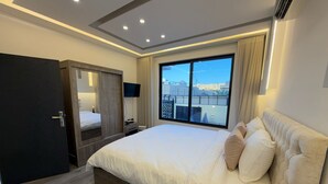 A modern hotel room with a large bed, a wardrobe, a TV, and a window with a city view. - ALYOUISIFYIACHALET (amman)