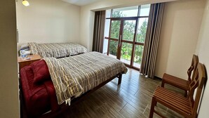 A hotel room with a bed, a chair, a nightstand, and a window with curtains. - Casa Ymelda Desaguadero (Desaguadero)