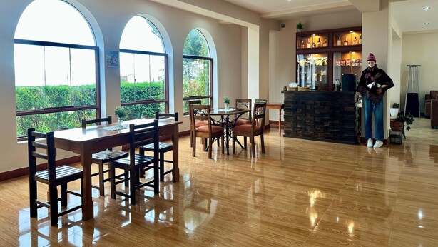 A spacious dining area with wooden furniture and large arched windows. - Casa Ymelda Desaguadero (Desaguadero)