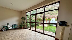 A spacious room with a large sliding glass door leading to a garden, a vintage Underwood Noiseless typewriter on a pedestal, and a green scooter against the wall. - Casa Ymelda Desaguadero (Desaguadero)