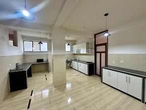 A modern kitchen with a central island, pendant lighting, and a view of the adjacent living area.