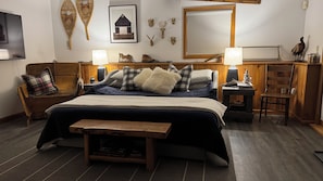 Ein Schlafzimmer mit einem Bett, Nachttischen, einer Lampe, einem Spiegel und Wanddekorationen.