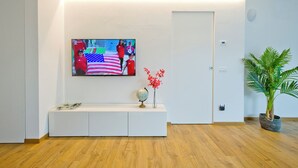 En moderne stue med et fladskærms-tv på væggen, et hvidt konsolbord, en globus og en potteplante.