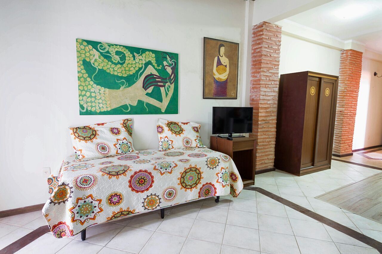 Una habitación con cama, televisión, armario y obras de arte en las paredes.