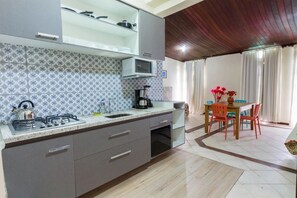A kitchen with a gas stove, microwave, and a dining area with a table and chairs. - Direita S.Antonio Direita S.Antonio -Charmant appartement baie de Todos Santos. (Salvador)