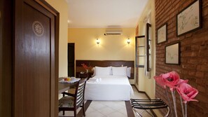 A hotel room with a bed, a dining table, chairs, a small table with a plate and a cup, and a brick wall with framed pictures. - Direita S.Antonio Direita S.Antonio -Charmant appartement baie de Todos Santos. (Salvador)