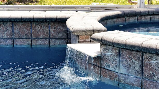 Piscina com cachoeira e paredes de pedra.