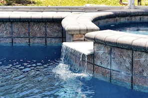 Piscina com cachoeira e paredes de pedra.