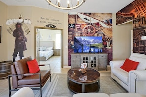 A modern living room with a large flat-screen TV, a cozy fireplace, and a bed in the background. - Happy Planet 1: Private Pool and Spa! BBQ Grill. (Davenport)