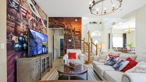 Uma sala de estar com televisão, mesa de centro, sofá e escada.