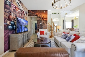A living room with a television, a coffee table, a sofa, and a staircase. - Happy Planet 1: Private Pool and Spa! BBQ Grill. (Davenport)