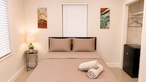Quarto com cama, luminária de cabeceira e obras de arte nas paredes.