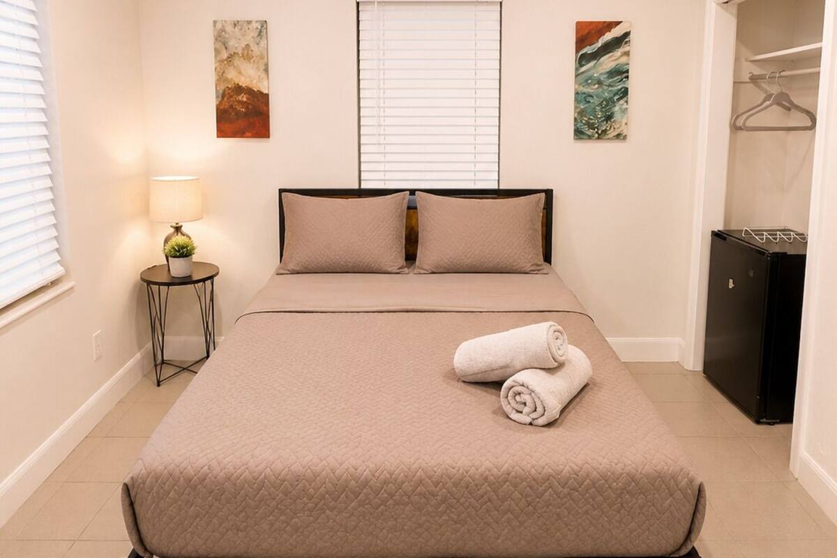 A bedroom with a bed, bedside lamp, and artwork on the walls.