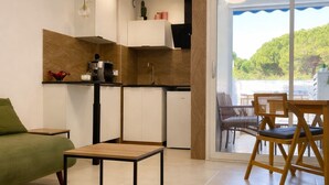 Una sala de estar moderna con un sofá verde, una mesa de centro de madera y un comedor con sillas de mimbre.