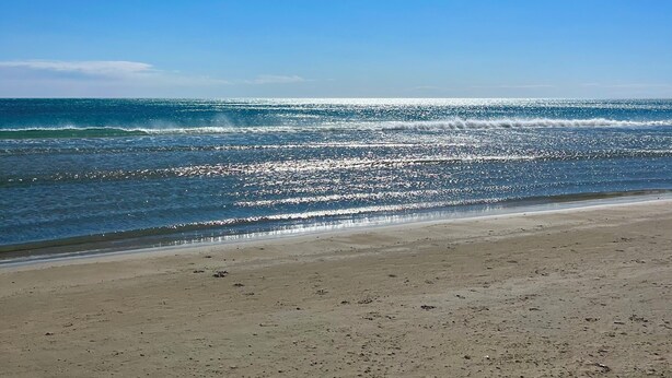 Una playa con cielo despejado y mar tranquilo.