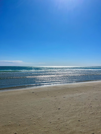 A beach with a clear sky and calm sea.. T1 beach with secure parking space