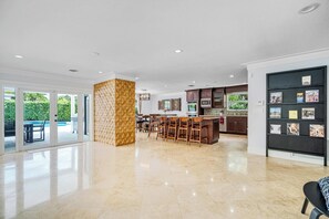A spacious kitchen with a central island, bar seating, and a built-in bookshelf. - Private Heated Pool Retreat for 6 (Hollywood)