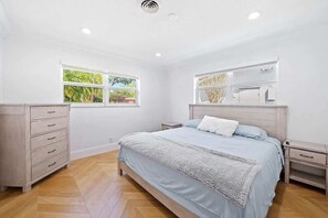 Ein Schlafzimmer mit einem Bett, einem Nachttisch, einer Kommode und einem Fenster.