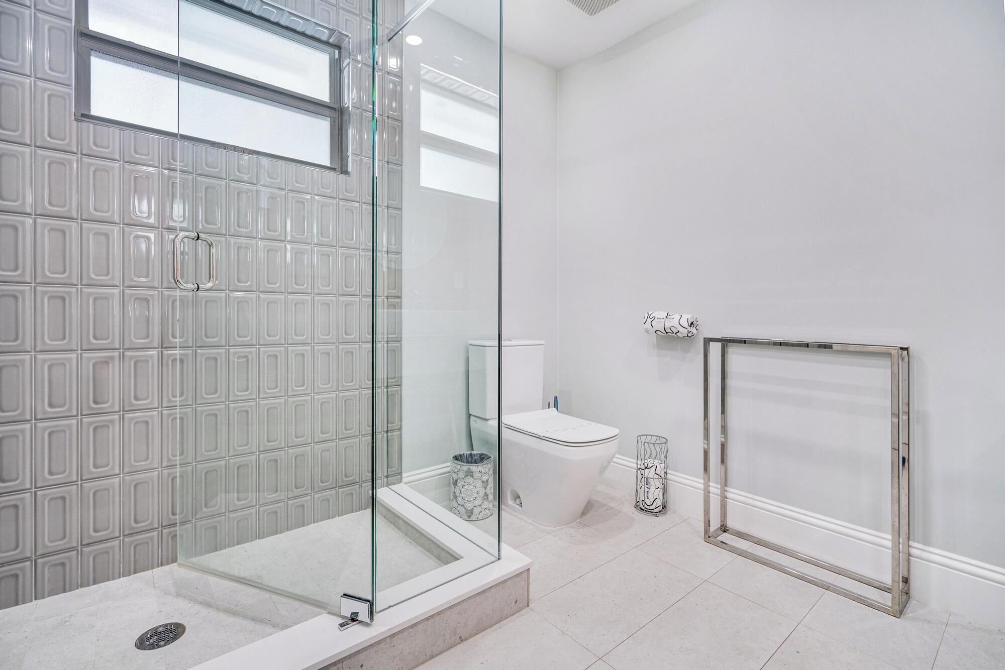 A modern bathroom with a glass-enclosed shower, a toilet, and a bathtub.