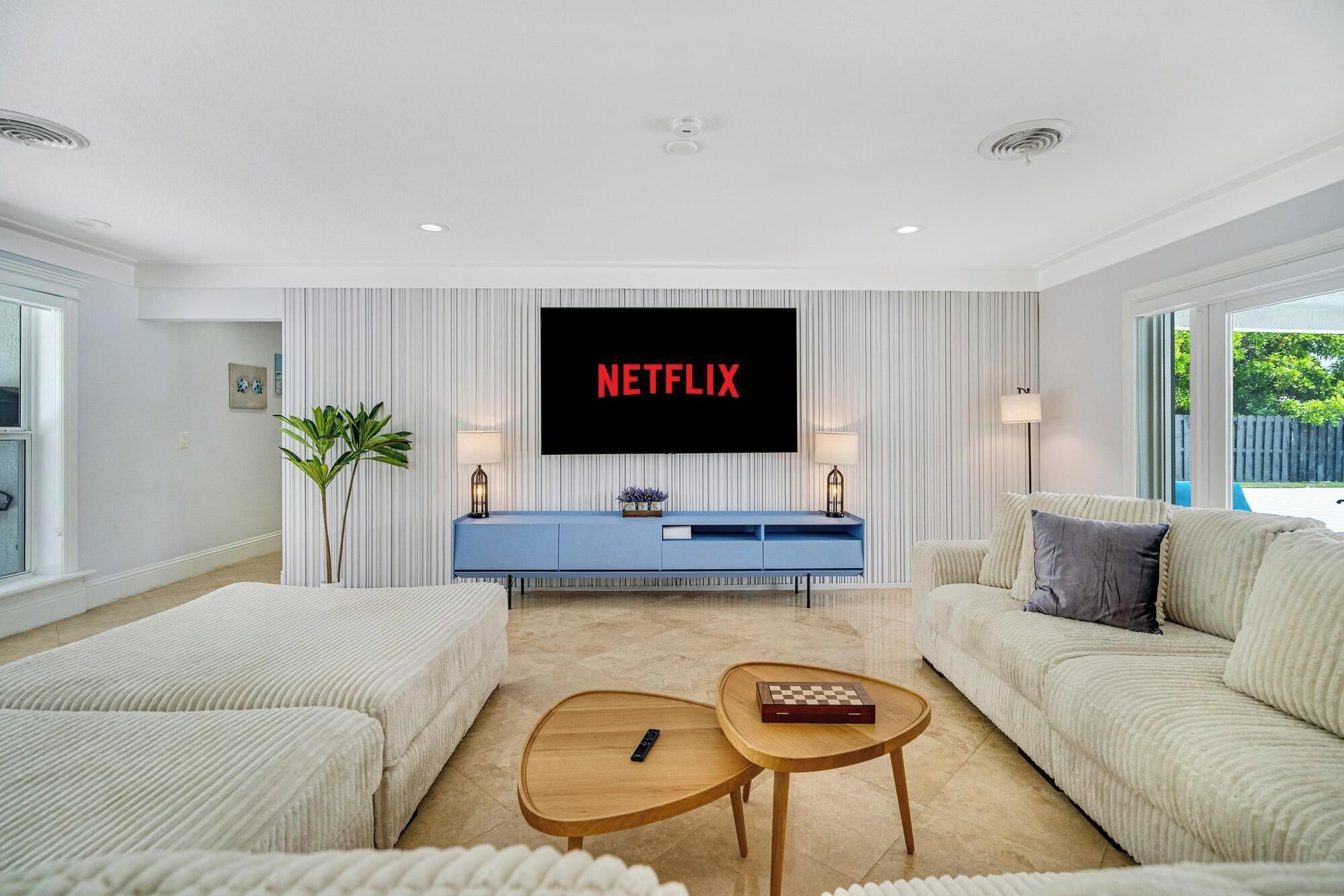 A modern living room with a large flat-screen TV mounted on the wall, a blue console table, two sofas, and a coffee table.