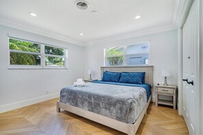 A bedroom with a bed, two bedside tables, a window, and a door. - Private Heated Pool Retreat for 6 (Hollywood)