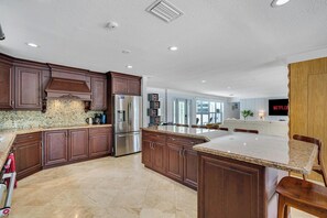 A modern kitchen with dark wood cabinets, stainless steel appliances, and a large island. - Private Heated Pool Retreat for 6 (Hollywood)