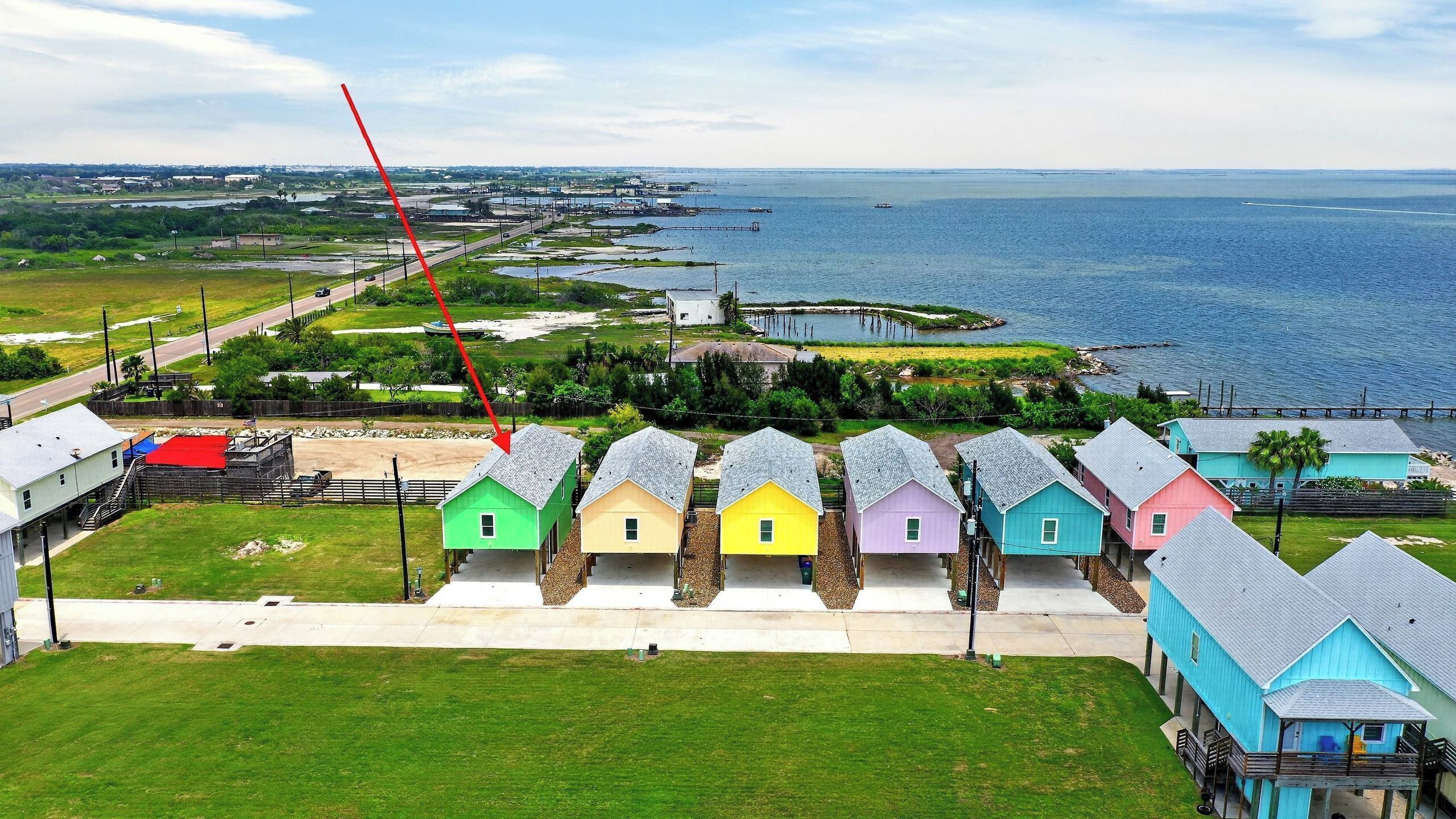 A coastal property with a row of colorful houses, a dock, and a view of the sea.