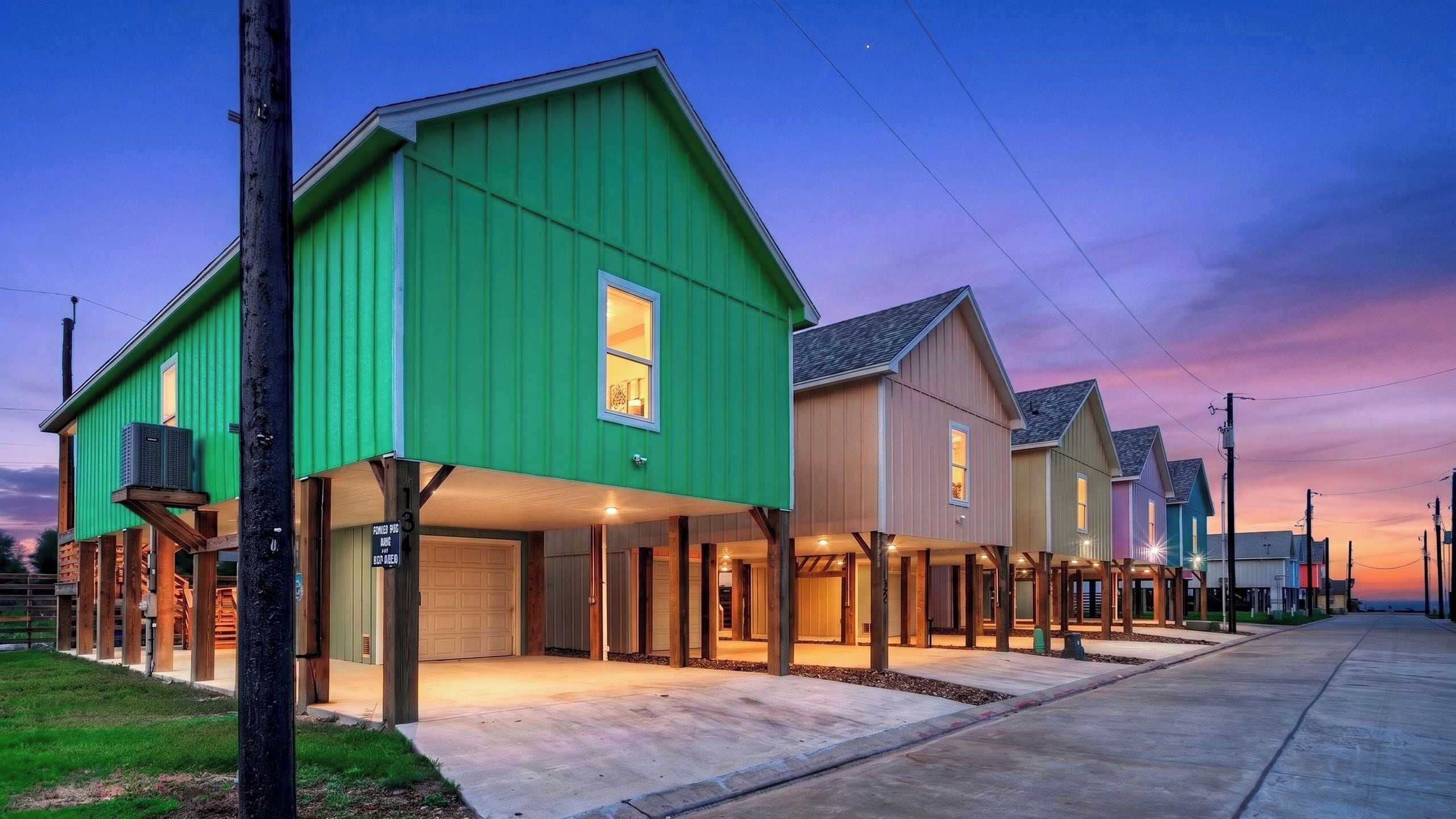 Une rangée de maisons modernes avec des garages attenants, une allée bien dégagée et un ciel au coucher du soleil.