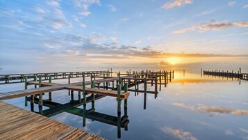 A wooden pier extending into calm water with a sunset in the background.