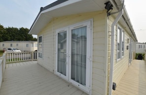 A single-story building with a covered deck, a sliding glass door, and a security camera.
