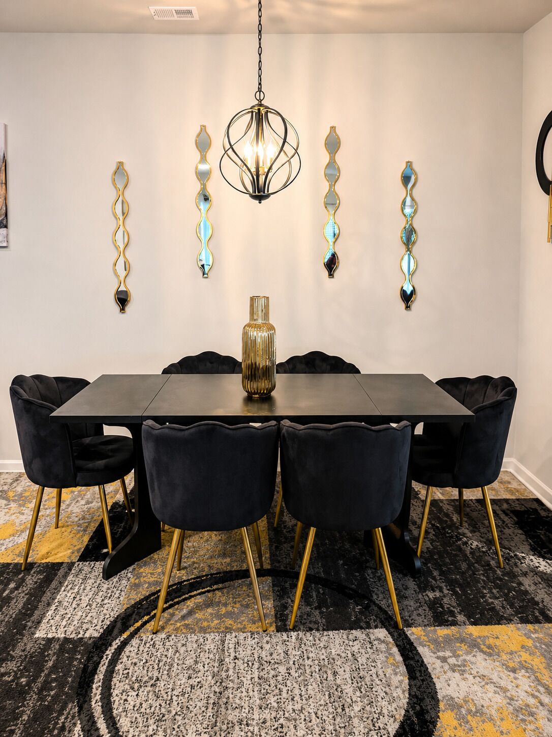 A dining area with a rectangular table, six chairs, a chandelier, and wall-mounted decorative mirrors.