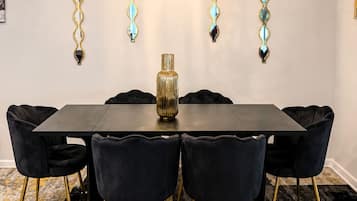 A dining area with a rectangular table, six chairs, a chandelier, and wall-mounted decorative mirrors.
