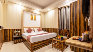 A hotel room with a bed, bedside table, chair, and a small table with snacks. - OnlyStay Aspire Inn Sector 44 Noida (Noida)