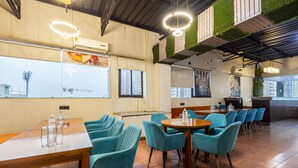 A restaurant with high ceilings, green wall accents, and a variety of seating arrangements including tables and chairs. - OnlyStay Aspire Inn Sector 44 Noida (Noida)